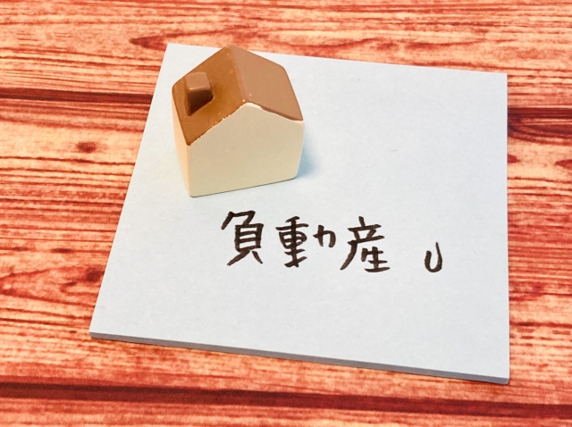 「負動産」と書かれたメモと家の模型