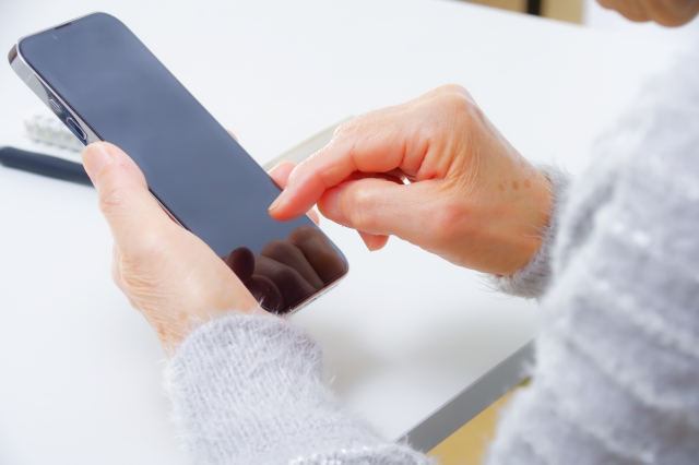 スマートフォンを操作する高齢女性の手元