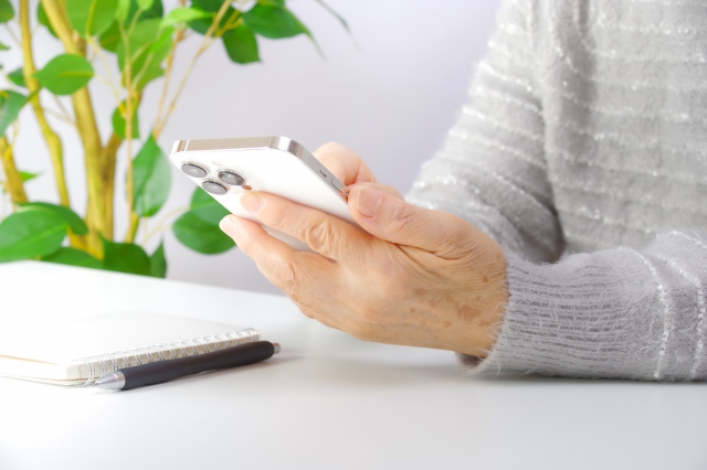 スマートフォンを持つ高齢女性の手元