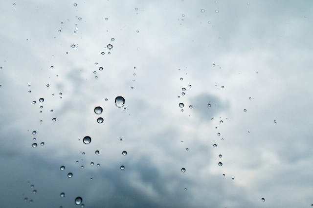 雨粒のついた窓と曇り空