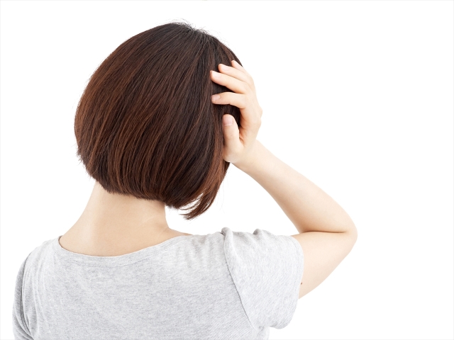 頭を押さえる女性の後ろ姿