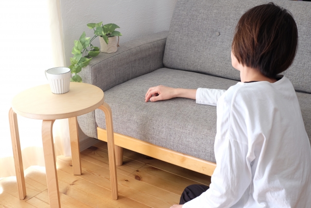 ソファのそばに座ってぼんやりする女性