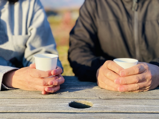 ベンチで飲み物を手にする二人