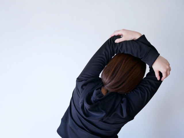 腕を伸ばしてストレッチをする女性の後ろ姿