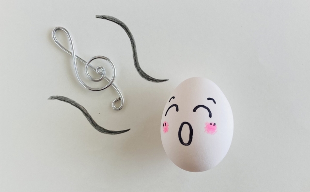口を開けた顔が描かれた卵とト音記号