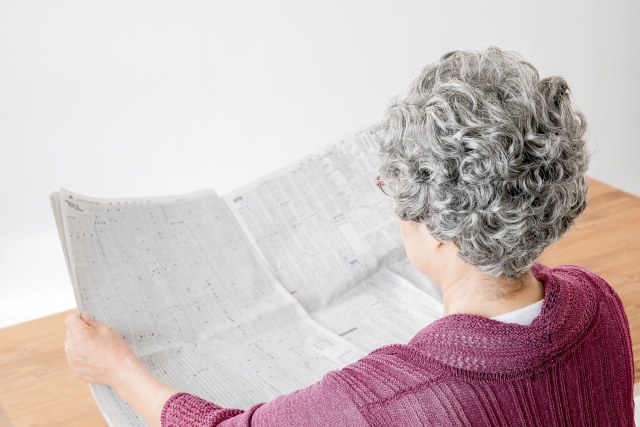 新聞を読む高齢女性の後ろ姿
